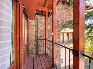 This stunning property boasts a charming balcony with intricate wooden detailing and a rustic stone facade.