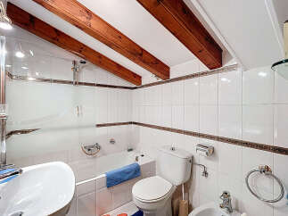 This charming bathroom features a unique design with exposed wooden beams and a slanted ceiling, creating a cozy and inviting atmosphere.