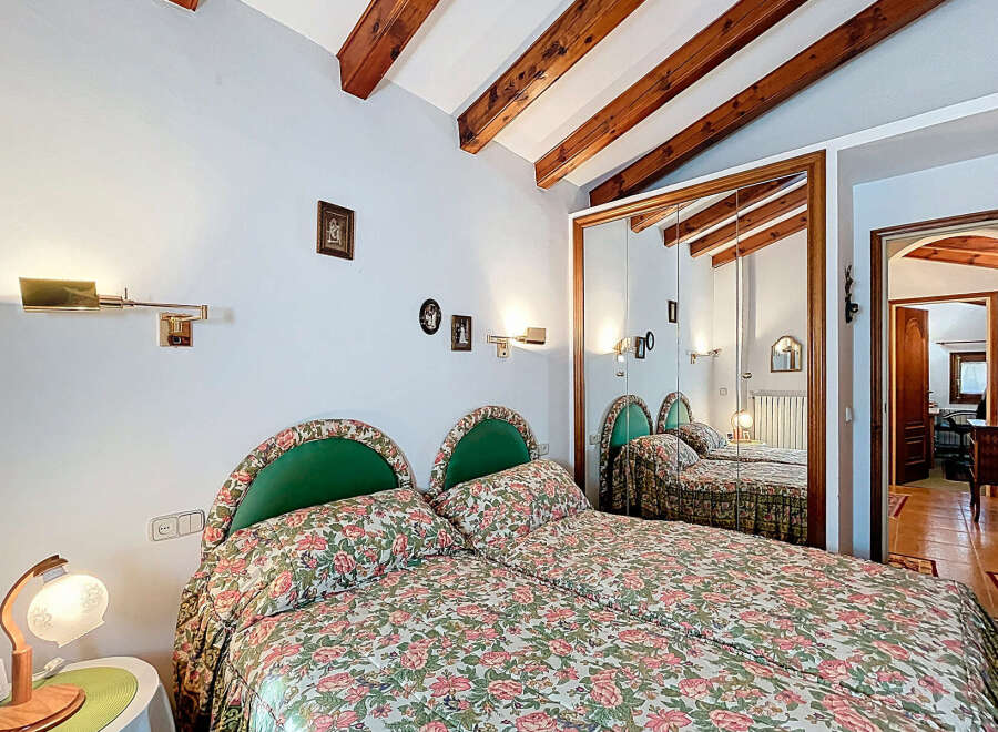 Discover the charm of this inviting bedroom, featuring a cozy double bed adorned with floral bedding and complemented by stylish green headboards.