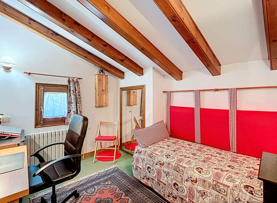 This charming bedroom features a cozy atmosphere with exposed wooden beams and a unique design.
