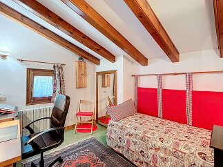 This charming bedroom features a cozy atmosphere with exposed wooden beams and a unique design.