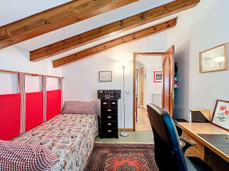 Discover the charm of this cozy bedroom, featuring a unique sloped ceiling with exposed wooden beams.
