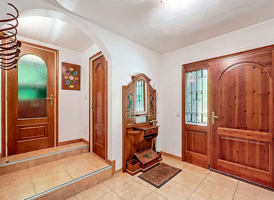 Step into this inviting entryway, featuring a charming wooden door and a decorative wall-mounted mirror.