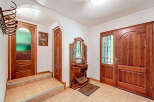 Step into this inviting entryway, featuring a charming wooden door and a decorative wall-mounted mirror.