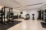 This modern home gym is equipped for a comprehensive workout, featuring a squat rack with weights, a flat bench, and a full set of dumbbells.