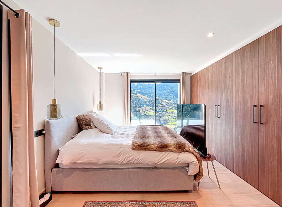Experience luxury in this stunning bedroom, featuring a plush bed and elegant pendant lighting.