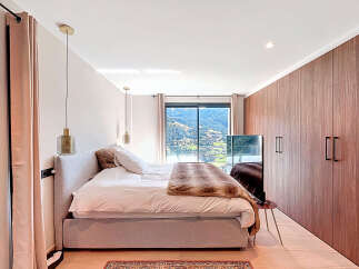 Experience luxury in this stunning bedroom, featuring a plush bed and elegant pendant lighting.