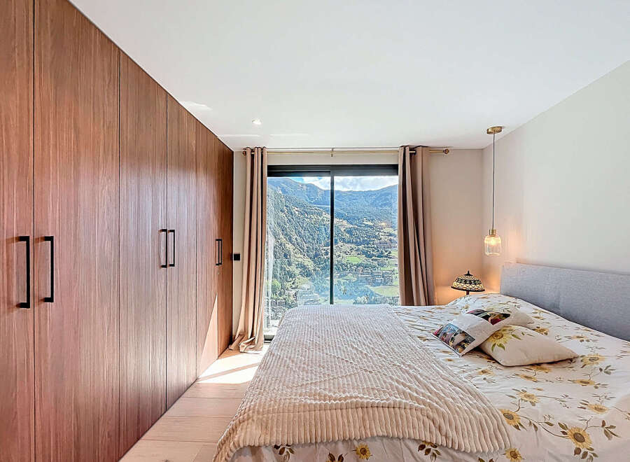 This stunning bedroom boasts a modern design with a large wardrobe and a breathtaking mountain view.