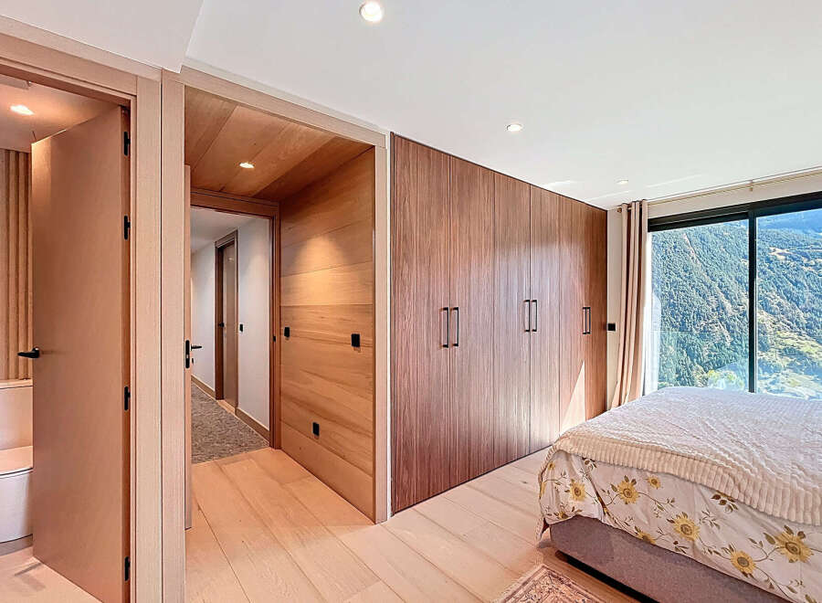 Experience luxury living in this stunning bedroom featuring exquisite wooden accents and a breathtaking mountain view.