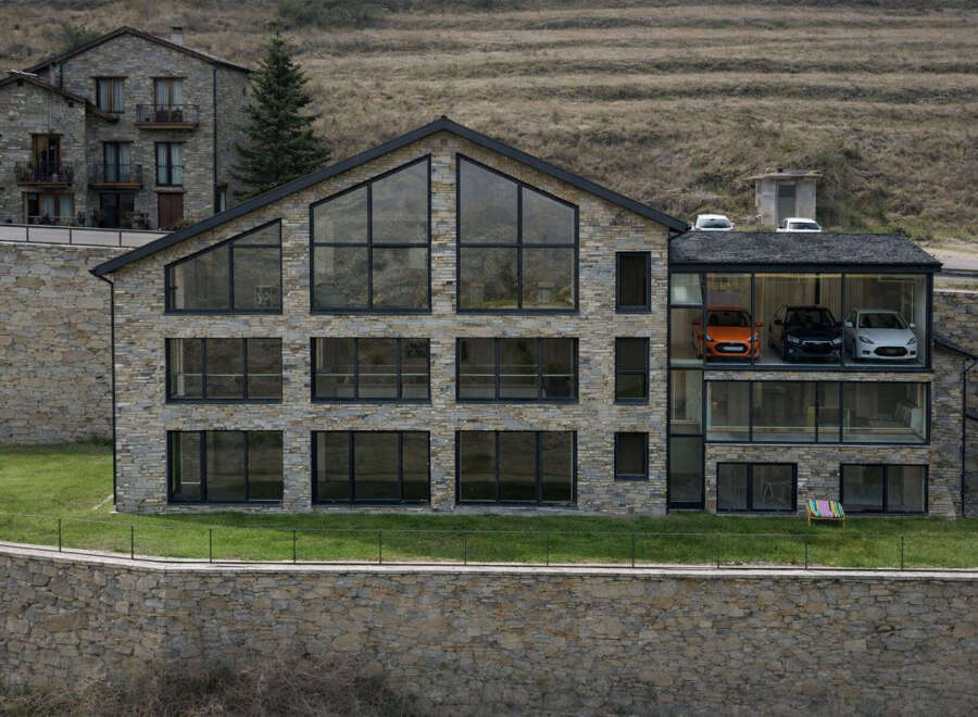 This stunning modern home showcases a unique design with a stone facade and expansive windows, offering breathtaking views.