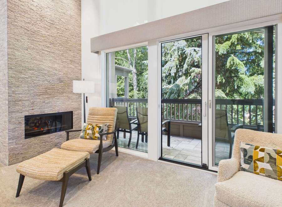 Experience modern living with this stunning living room featuring a sleek, stacked stone fireplace and expansive sliding glass doors that open to a private balcony.