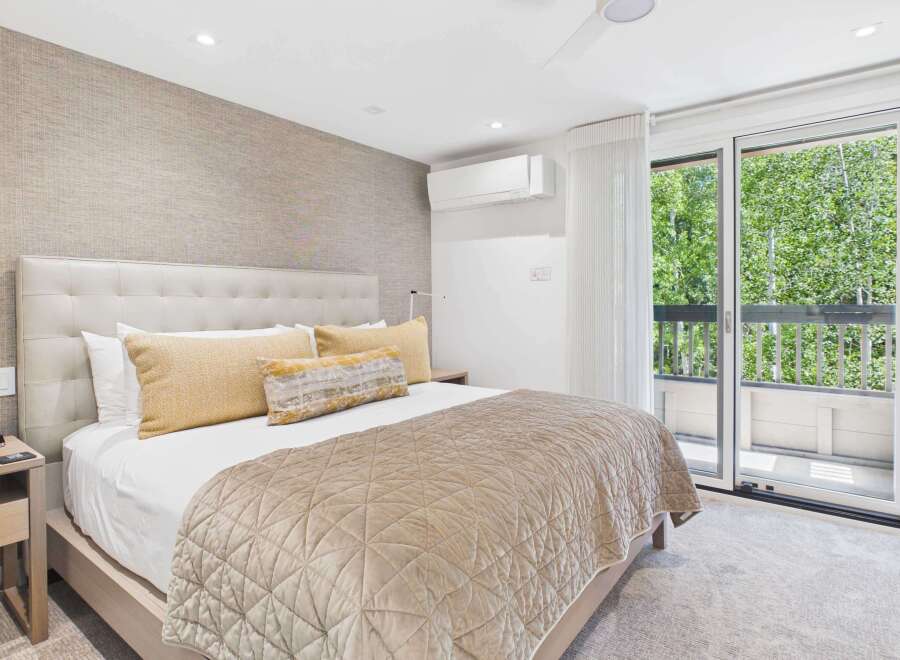 Experience ultimate comfort in this luxurious bedroom featuring a plush king-sized bed with a tufted headboard and elegant gold accent pillows.