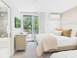 Experience ultimate comfort in this beautifully appointed bedroom featuring a plush king-sized bed adorned with luxurious linens and decorative pillows.