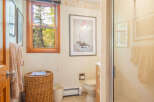 This charming bathroom features a cozy atmosphere with a wicker basket, a window with a view, and a framed artwork.