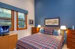 This cozy bedroom features a comfortable bed with a plaid comforter and matching pillows, perfect for a relaxing stay.
