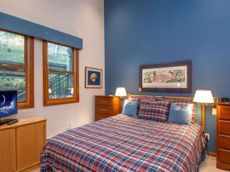 This cozy bedroom features a comfortable bed with a plaid comforter and matching pillows, perfect for a relaxing stay.