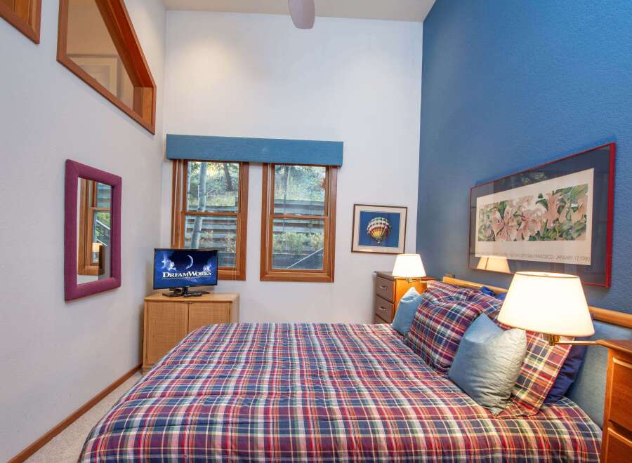 This cozy bedroom features a comfortable plaid bed, perfect for relaxing after a long day.