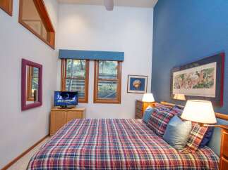 This cozy bedroom features a comfortable plaid bed, perfect for relaxing after a long day.