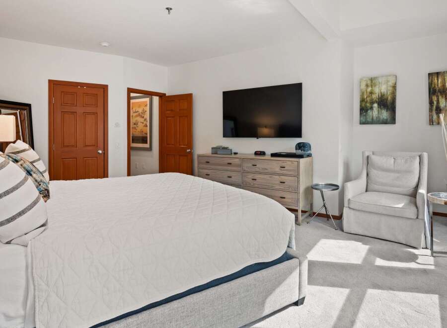 This spacious bedroom offers a serene retreat with its neutral color palette and ample natural light.