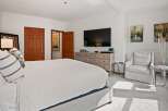 This spacious bedroom offers a serene retreat with its neutral color palette and ample natural light.