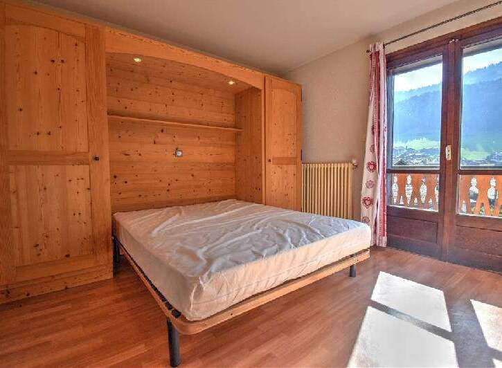 Discover this charming bedroom featuring a built-in wooden bed frame and ample storage.