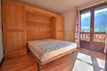 Discover this charming bedroom featuring a built-in wooden bed frame and ample storage.