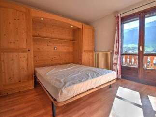 Discover this charming bedroom featuring a built-in wooden bed frame and ample storage.