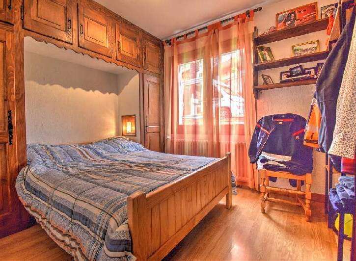 Discover the charm of this cozy bedroom, featuring a built-in wooden bed frame and ample storage cabinets.