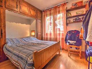 Discover the charm of this cozy bedroom, featuring a built-in wooden bed frame and ample storage cabinets.