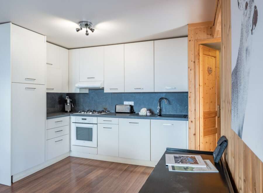 This modern kitchen features sleek white cabinetry and a dark countertop, creating a clean and stylish look.