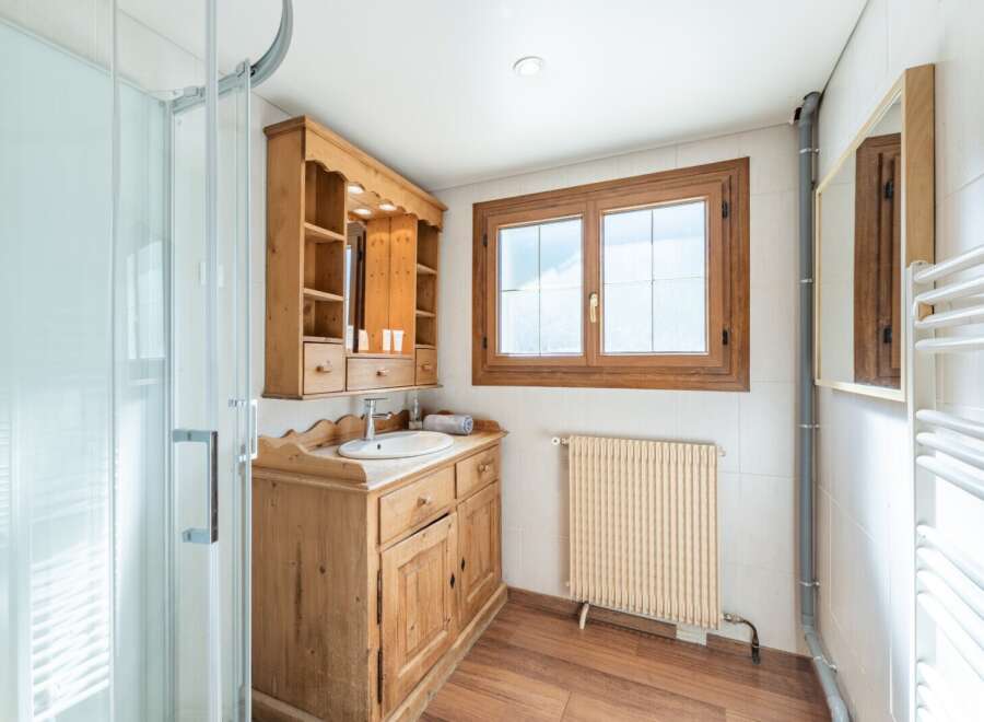 Discover the charm of this beautifully designed bathroom, featuring a rustic wooden vanity and a stylish shower enclosure.