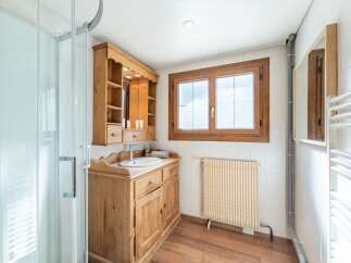 Discover the charm of this beautifully designed bathroom, featuring a rustic wooden vanity and a stylish shower enclosure.