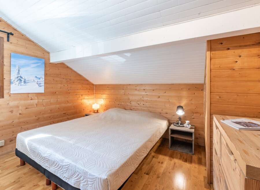 This cozy bedroom features beautiful wooden paneling and a comfortable bed, creating a warm and inviting atmosphere.