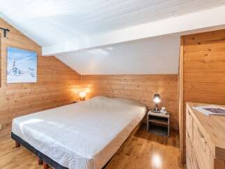This cozy bedroom features beautiful wooden paneling and a comfortable bed, creating a warm and inviting atmosphere.