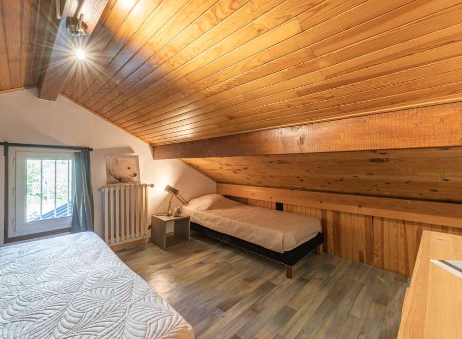 Discover the charm of this cozy bedroom with its unique sloped ceiling and wooden accents.