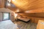 Discover the charm of this cozy bedroom with its unique sloped ceiling and wooden accents.
