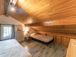 Discover the charm of this cozy bedroom with its unique sloped ceiling and wooden accents.