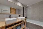This modern bathroom features a sleek design with a double vanity and a spacious bathtub.
