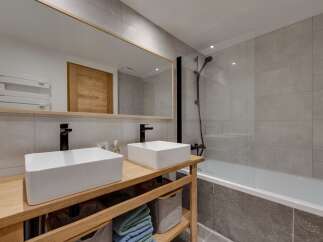 This modern bathroom features a sleek design with a double vanity and a spacious bathtub.
