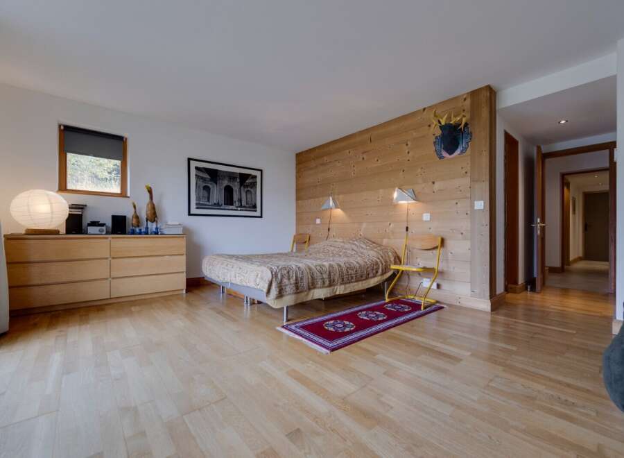 This inviting bedroom features a cozy bed with a unique patterned cover, set against a backdrop of warm wooden paneling.