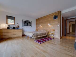 This inviting bedroom features a cozy bed with a unique patterned cover, set against a backdrop of warm wooden paneling.