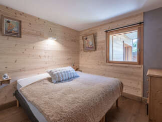 This cozy bedroom features beautiful wooden paneling and a comfortable bed, creating a warm and inviting atmosphere.