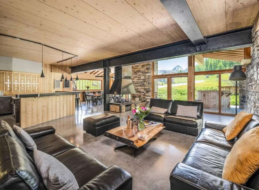 Experience luxury living in this stunning chalet, featuring a spacious living area with a cozy fireplace and comfortable seating.