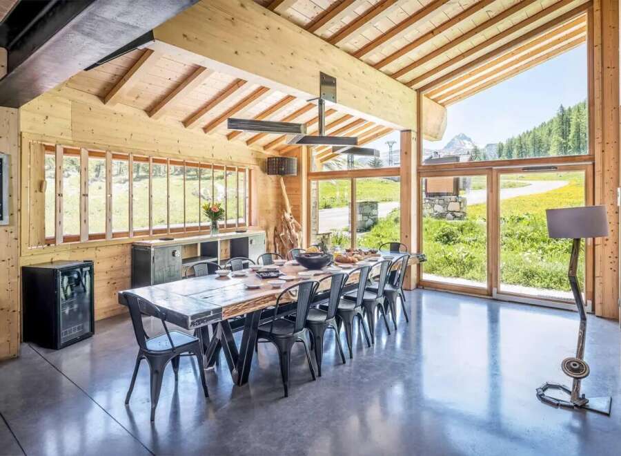 Experience luxury living in this stunning property, featuring a spacious dining area with a rustic wooden table and sleek metal chairs.
