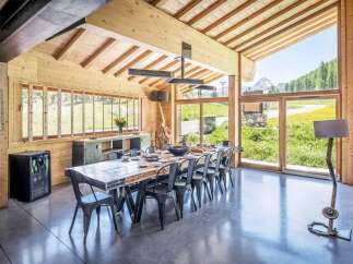 Experience luxury living in this stunning property, featuring a spacious dining area with a rustic wooden table and sleek metal chairs.