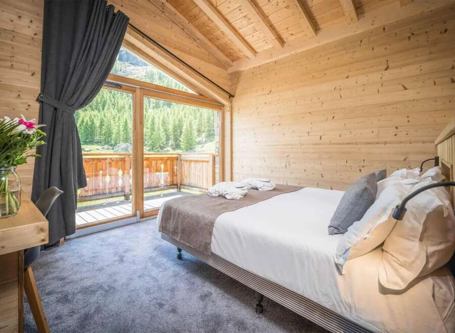 Experience the tranquility of this stunning bedroom, featuring a cozy bed and a breathtaking view of the surrounding nature.