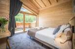 Experience the tranquility of this stunning bedroom, featuring a cozy bed and a breathtaking view of the surrounding nature.
