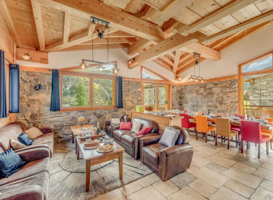 Experience luxury living in this stunning chalet, featuring a warm and inviting interior with exposed wooden beams and stone walls.