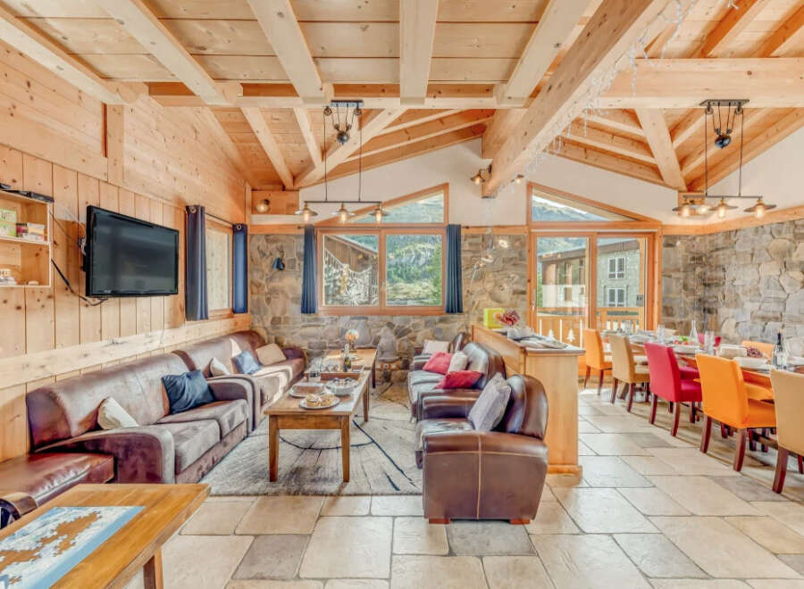 Experience the charm of this stunning chalet, featuring a cozy living area with comfortable leather sofas and a large TV.