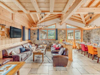 Experience the charm of this stunning chalet, featuring a cozy living area with comfortable leather sofas and a large TV.
